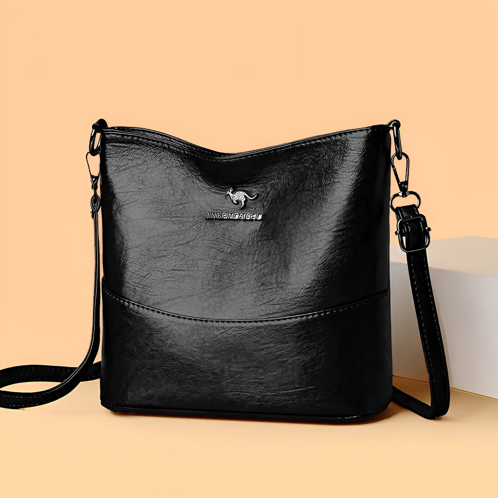 Women's soft leather bucket shoulder bag in black, shown with minimalist design and sewing line detail.