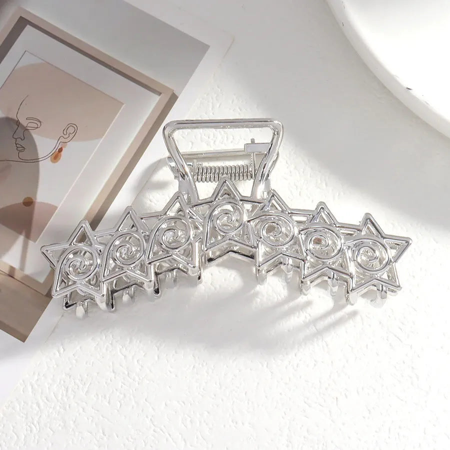 Assortment of silver metal hair claw barrettes with various designs including bows, pearls, and geometric shapes.