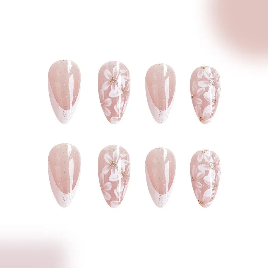 Short almond shaped press-on nails with French style glitter floral designs on a glossy background.