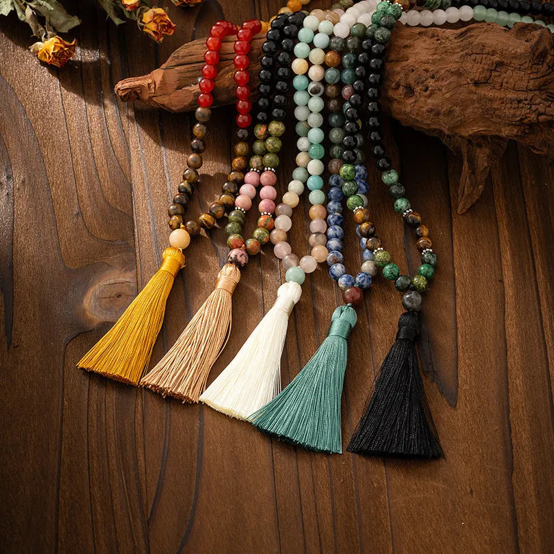 Long natural stone beaded sweater chain necklace and matching bracelet in bohemian style on a grey background.