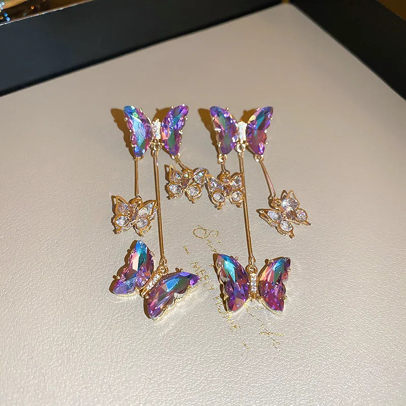 Silver electroplated alloy drop earrings with a blue purple butterfly charm and crystal flower details on a tassel.