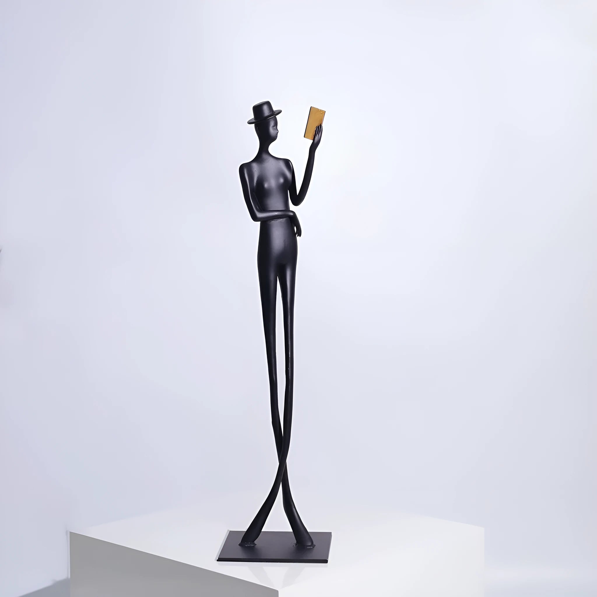 Black cast aluminium reading woman sculpture on desktop, 12 cm wide by 51 cm high