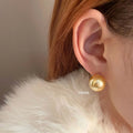 A pair of large geometric pearl stud earrings with an eight-point star detail on silver settings.