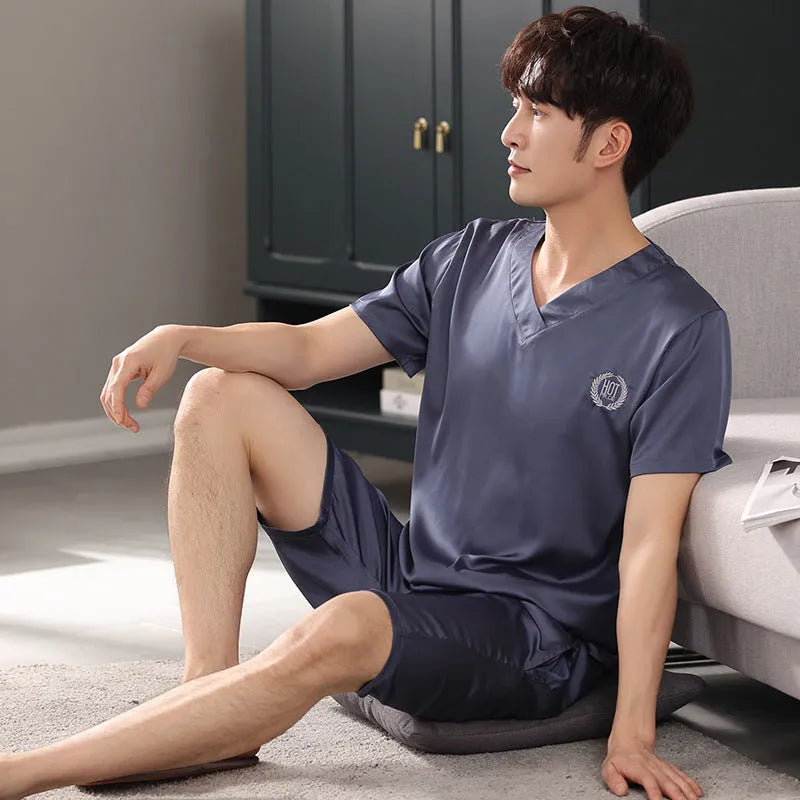 Man wearing a loose light blue short-sleeve pajama shirt and matching shorts, labelled as ice silk sleepwear.