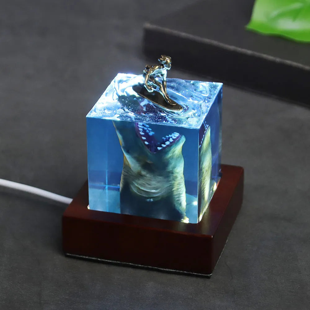 Epoxy resin shark surfer night light ornament on a desk, showing 5cm and 8cm size options.