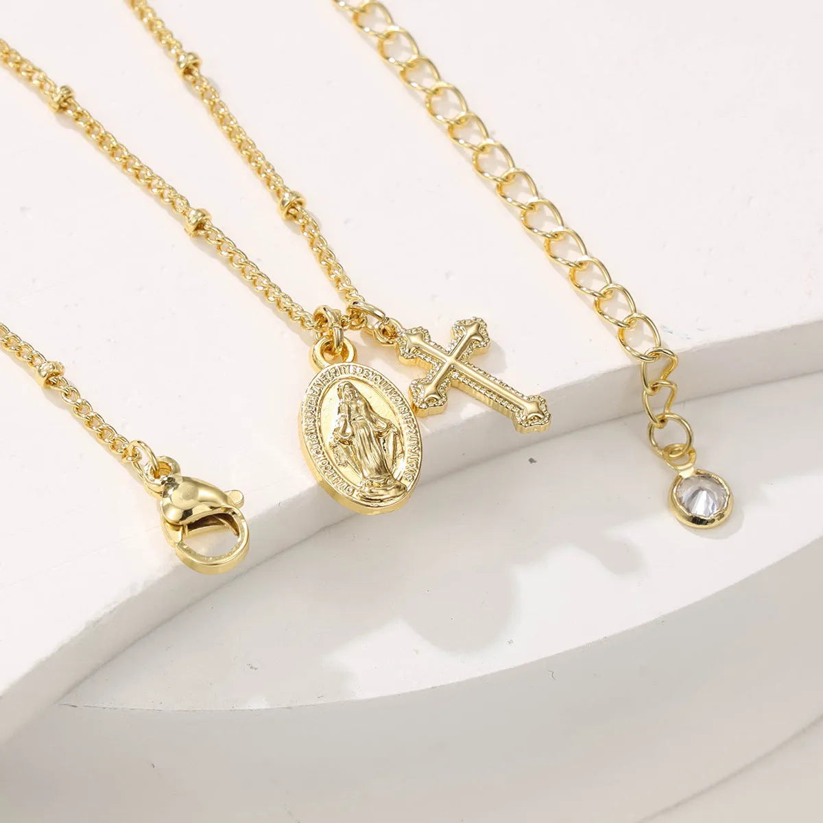 Gold Virgin Mary and cross geometric pendant necklace on a simple chain.