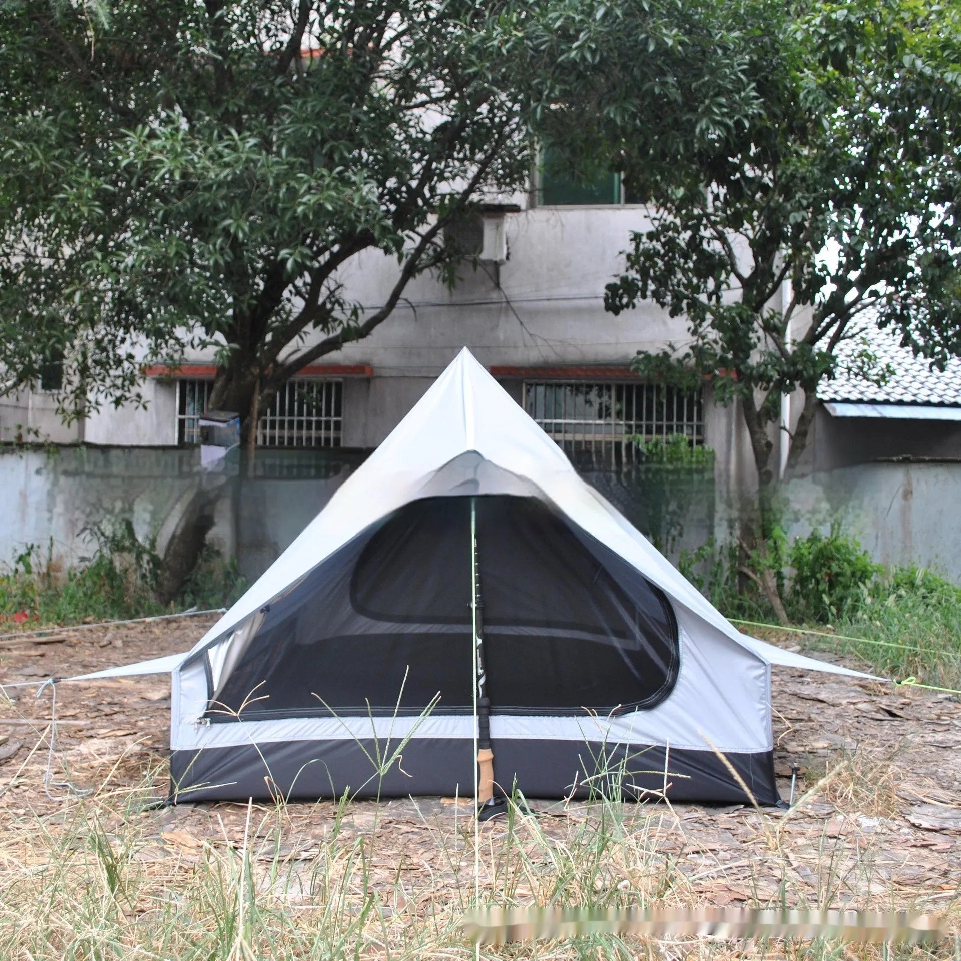 Brown A-line cabin tent pitched with hiking poles as structural support showing spacious interior for 2-3 people