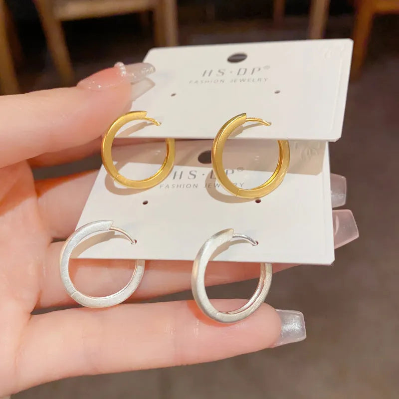 Geometric gold-plated ear clip with round eyelet detail on white background