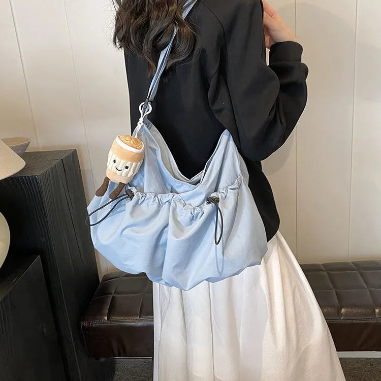 Ultra-light pleated green crossbody cloth bag lying flat, showing its split pocket and foldable design.