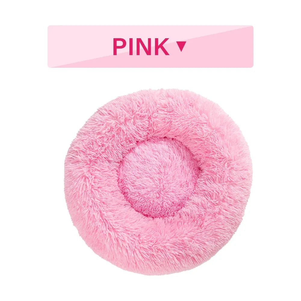 Fluffy donut-shaped dog bed in long plush fabric, shown in a light grey colour with a raised edge.