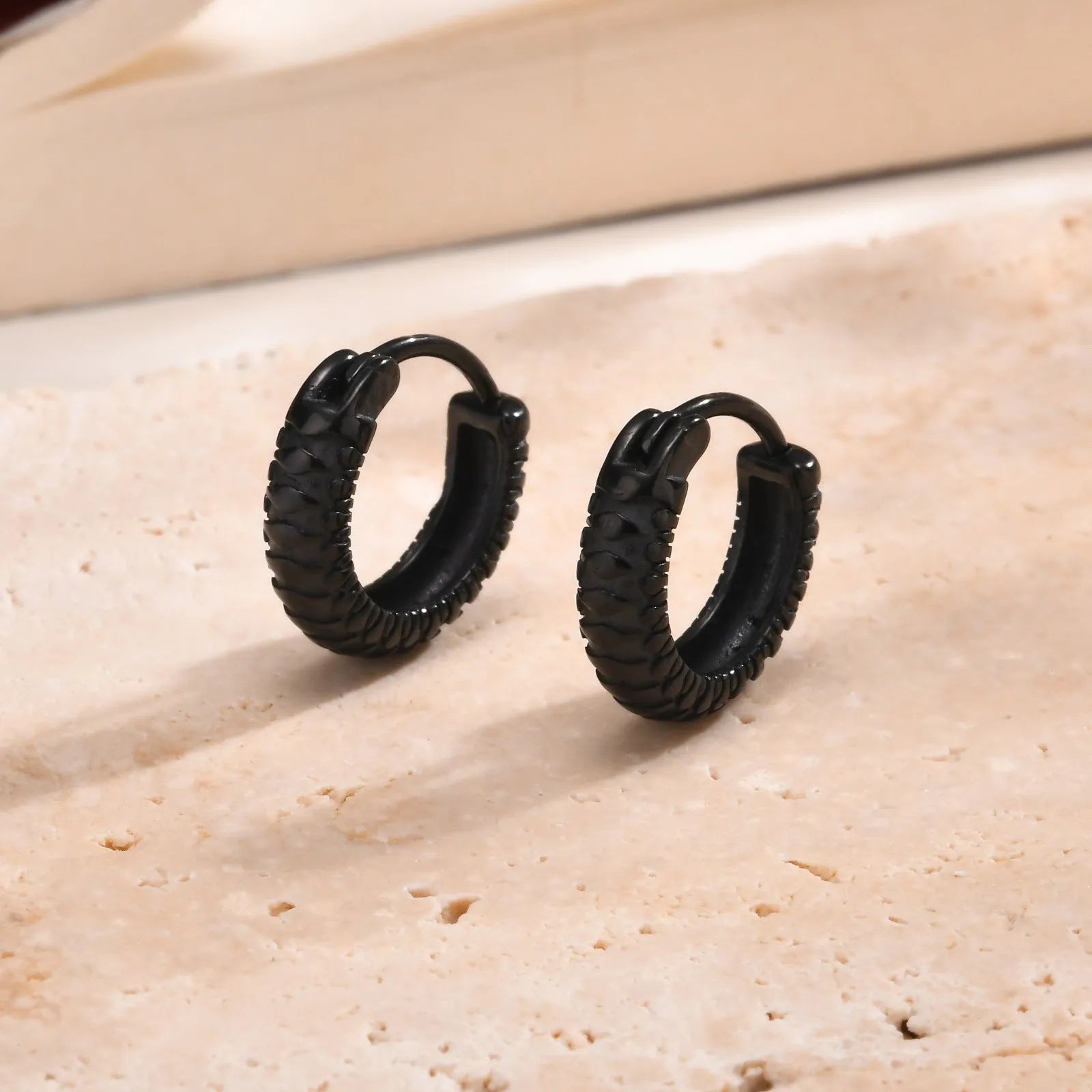A pair of stainless steel earrings with a snake pattern design in black or gold.