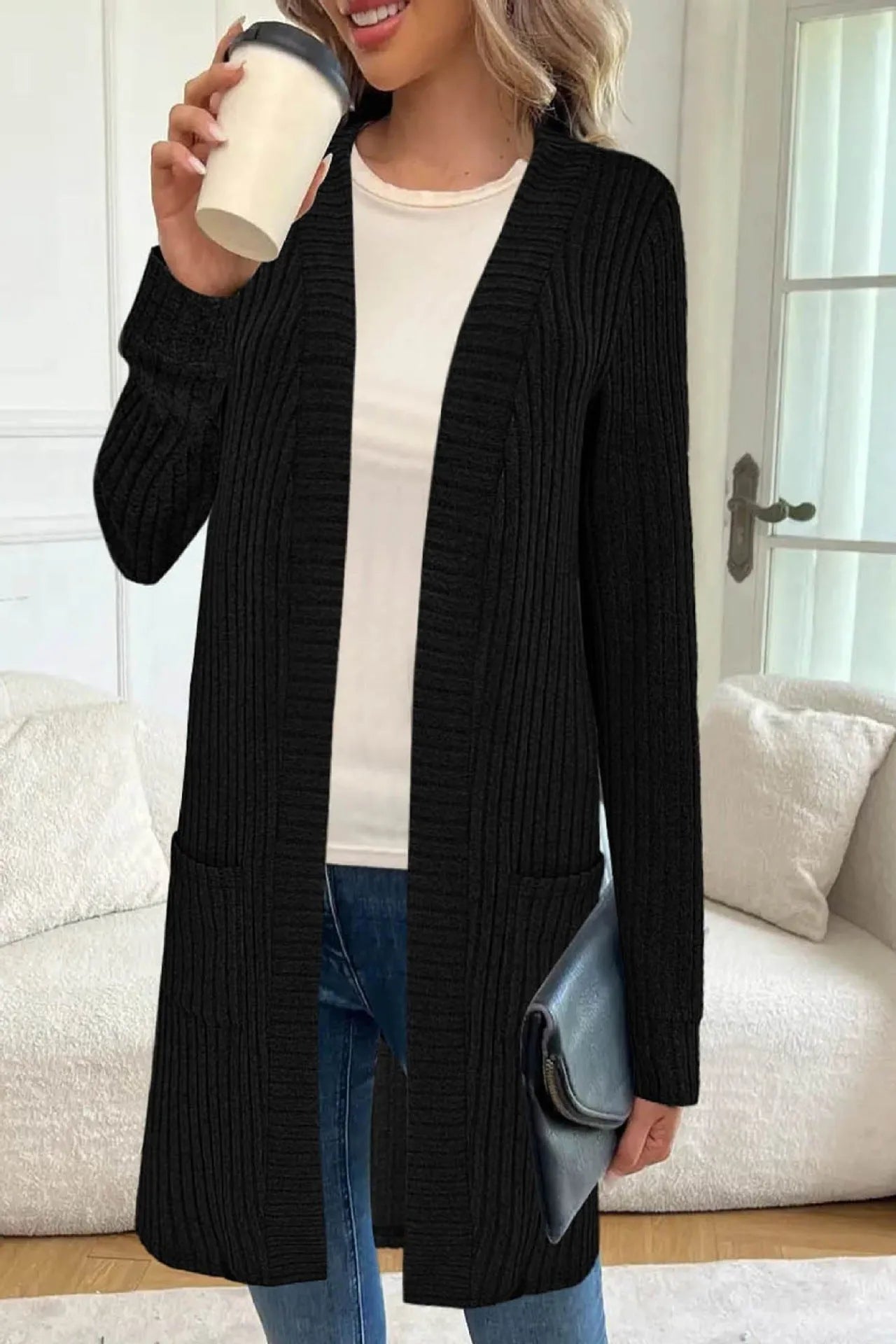 Long sleeve loose fit knitted cardigan jacket in black, shown with two front pockets.