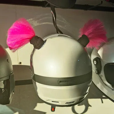 Pair of decorative braided balls for helmet customisation next to a tube of adhesive