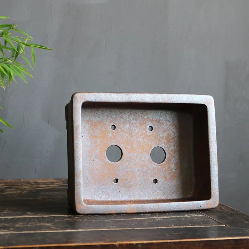 Rectangular purple sand bonsai pot with firewood burning texture on a floor.