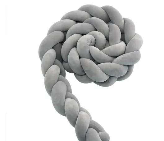 Braided knot style baby crib bumper in a light grey colour, shown lined inside a white wooden cot.