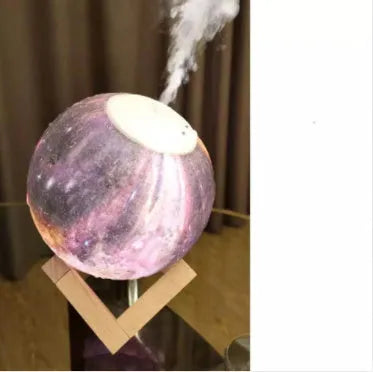 White spherical lunar humidifier night light with USB charging cable on a wooden surface.