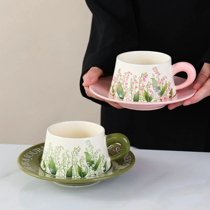 Ceramic coffee cup and saucer set with two spoons, shown in campanula and lanling grass designs.