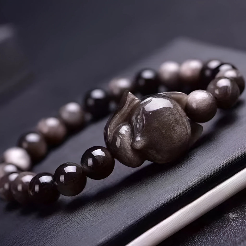 Adjustable obsidian bracelet with a single polished 8mm bead carved with a fox design.