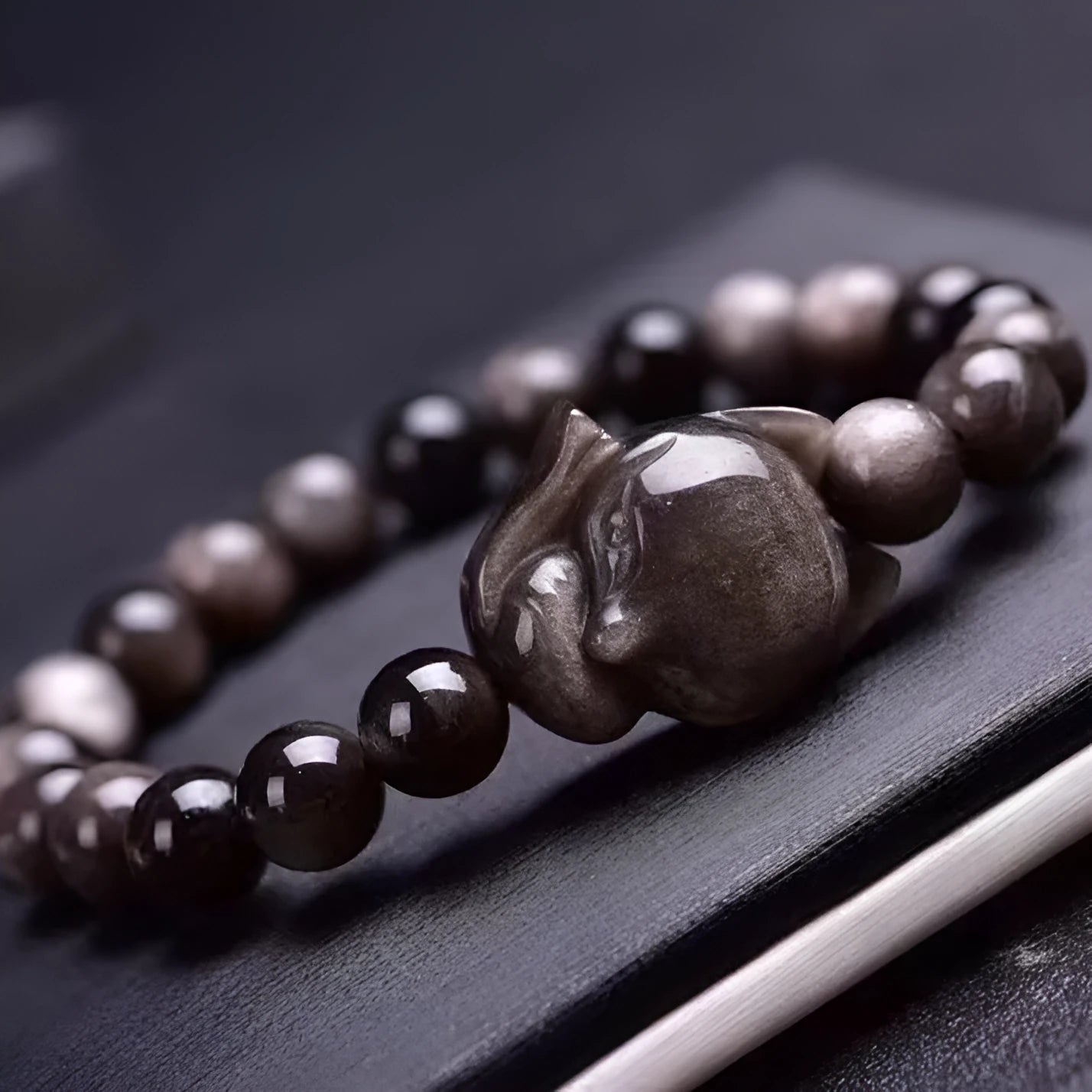 Adjustable obsidian bracelet with a single polished 8mm bead carved with a fox design.