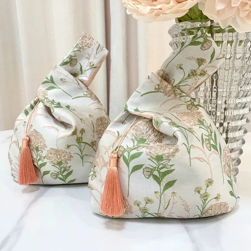 Chinese style gold silk jacquard hand-held cloth gift bag with flower accent in champagne colour on white background