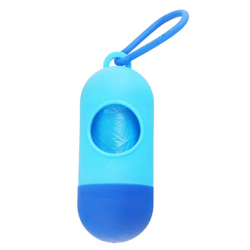 Compact black dog poop bag holder with Velcro strap and metal side hook, shown next to a roll of waste bags.