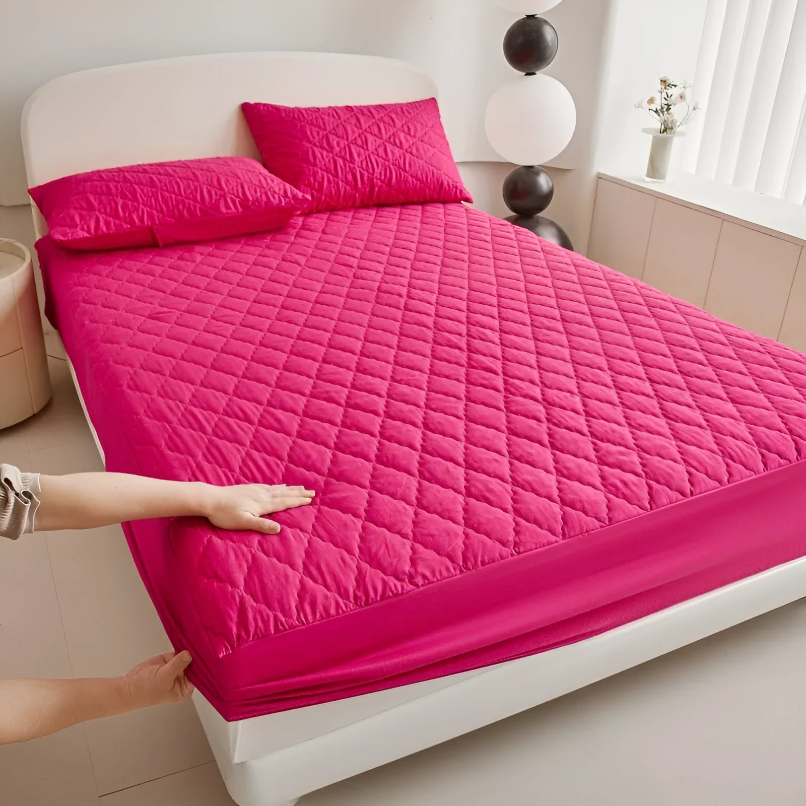 Diamond lattice quilted waterproof mattress protector fitted sheet in a solid colour on a bed.