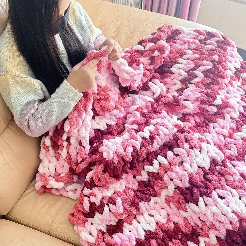 Coarse yarn chenille knitted blanket with braided gravity trim in a modern colour on a bed.