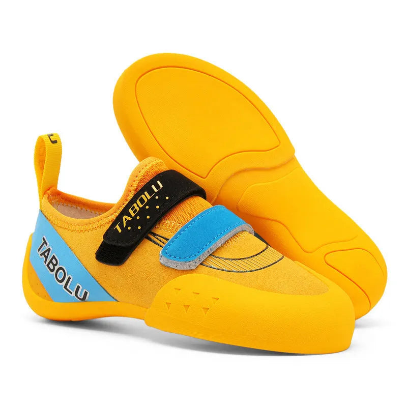 Pair of beginner rock climbing shoes with Velcro strap and black and red rubber outsole.