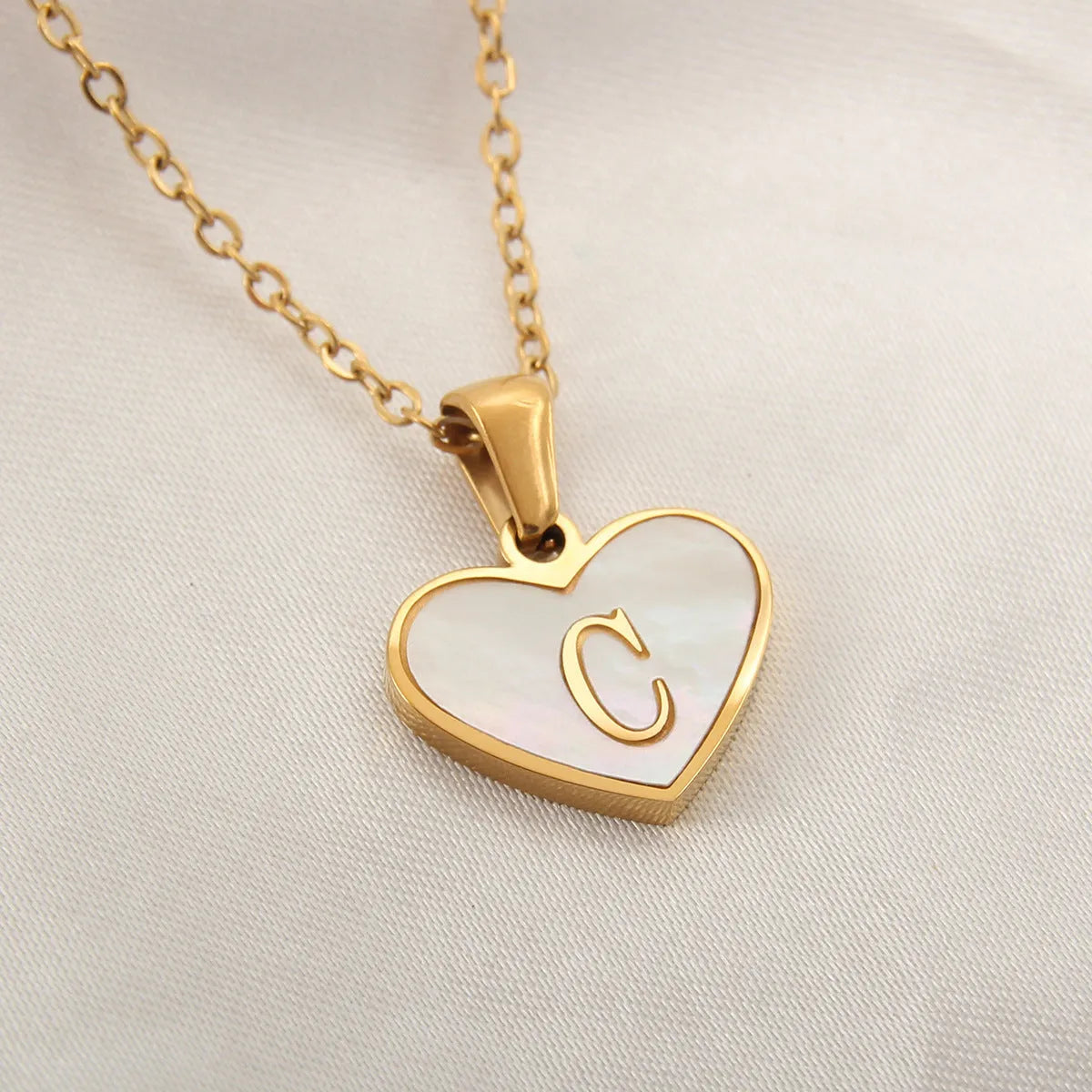 Gold plated heart-shaped white shell pendant personalised initial necklace on a stainless steel chain.