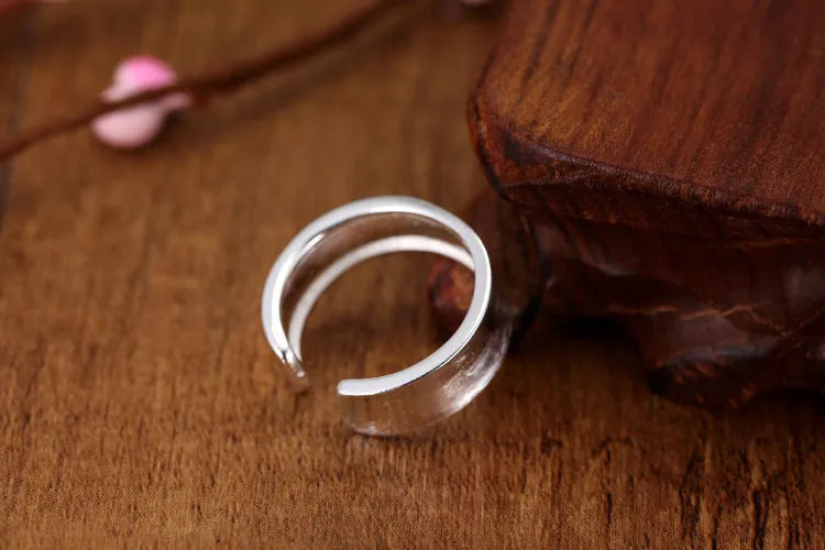 Geometric open ring with adjustable size in frosted sterling silver on a grey background.