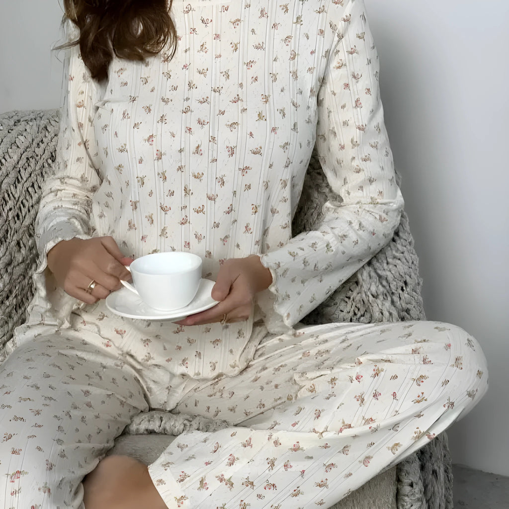 White floral print women's two-piece suit with bell sleeve top and wide leg trousers laid flat.