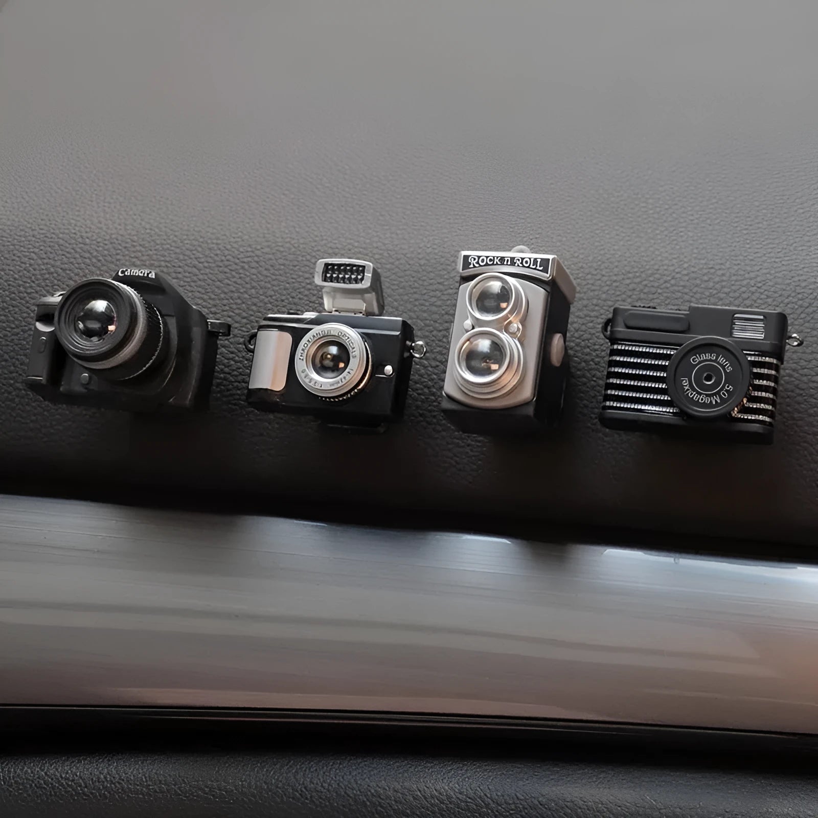Set of four retro camera dot design plastic adhesive hooks for car dashboard organisation.