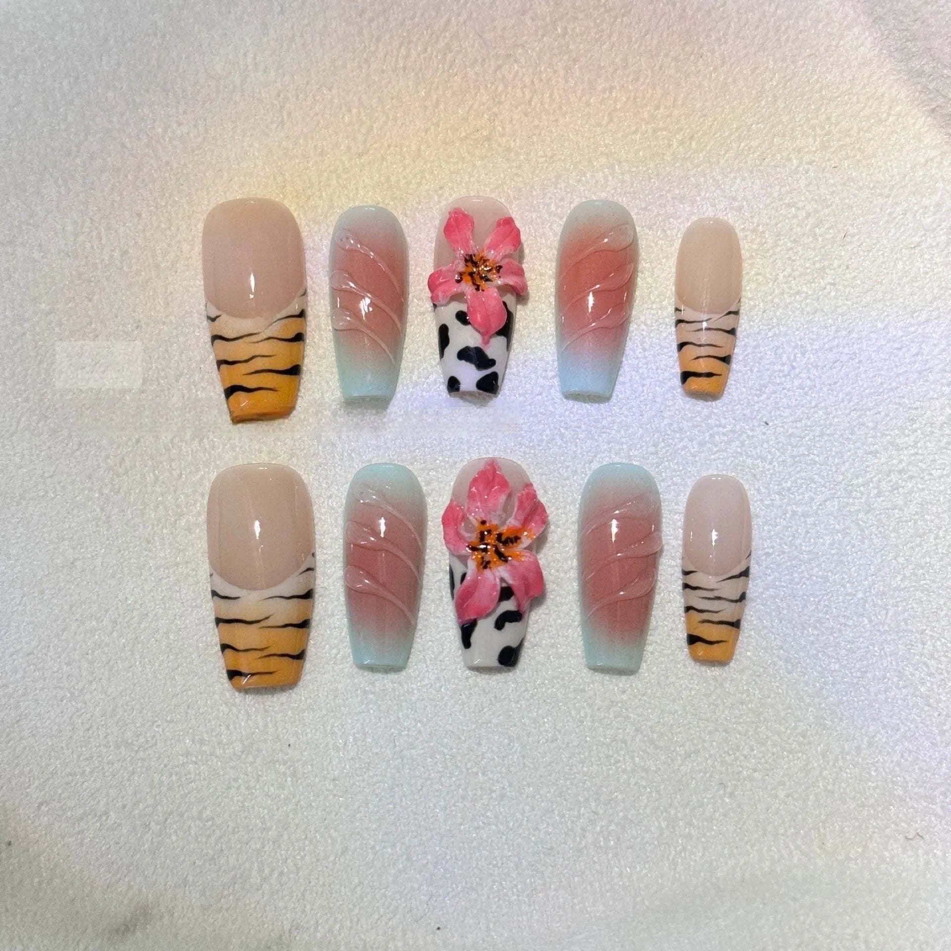 False nails with zebra pattern, carved lily design, and leopard print in long wear-resistant style.