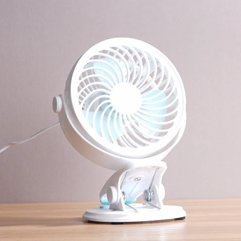 Compact USB desktop fan shown as both a clip-on model and a floor-standing model on a wooden desk.