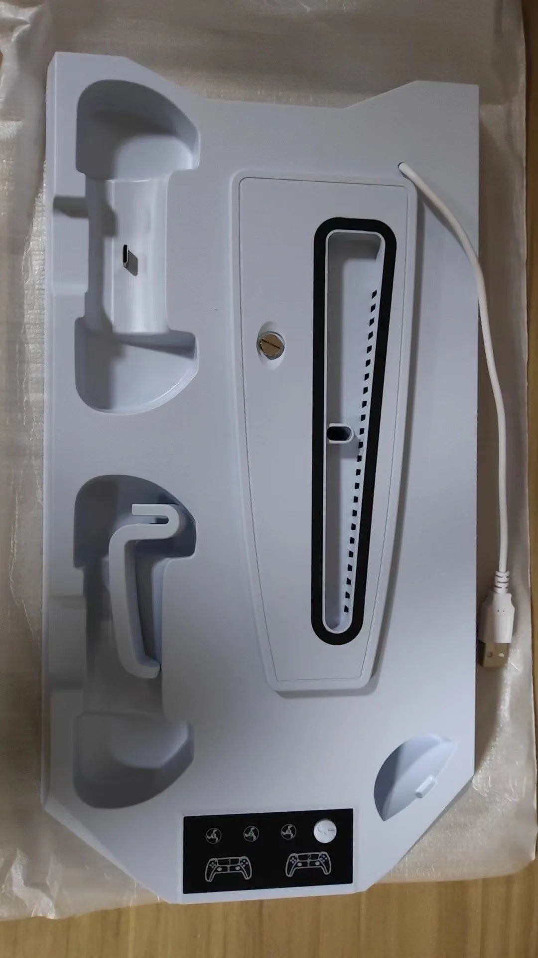 White PS5 charging dock and cooling base station with controllers and headset on display
