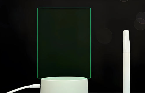 Black 3D acrylic message board night light on desk with remote control and stylus.