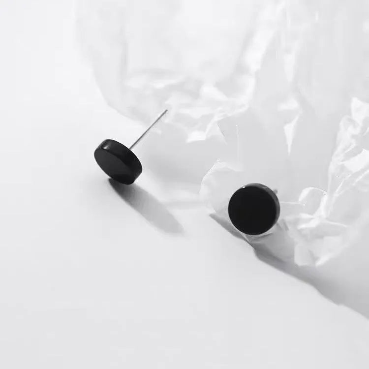 A pair of simple round S999 sterling silver flat ear bone studs on a plain background.