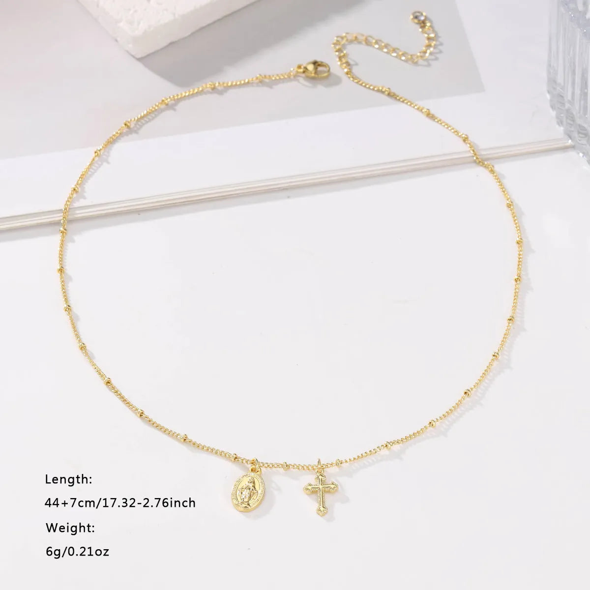 Gold Virgin Mary and cross geometric pendant necklace on a simple chain.