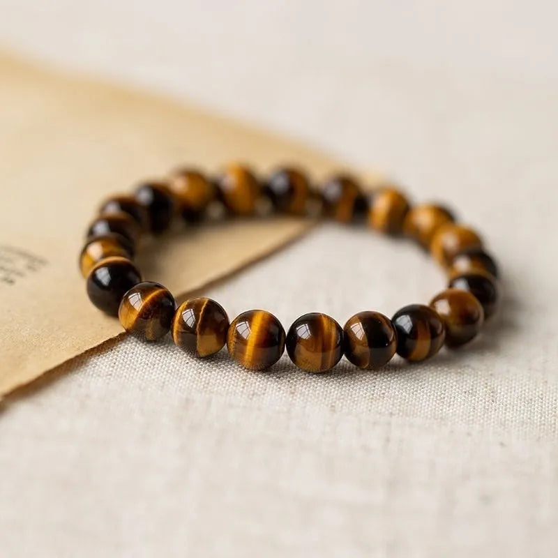 Close-up of a single-circle beaded Buddha rosary bracelet with tigereye dzi patterns on brown beads.