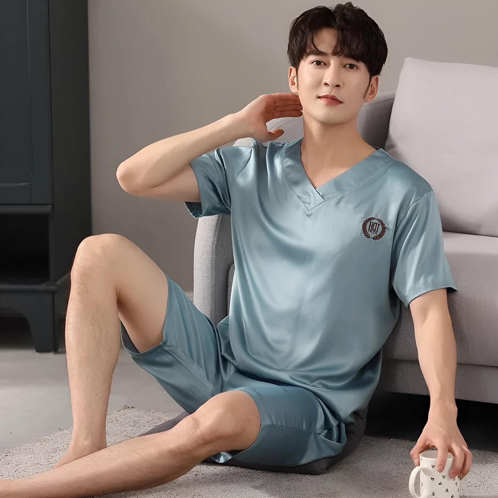 Man wearing a loose light blue short-sleeve pajama shirt and matching shorts, labelled as ice silk sleepwear.