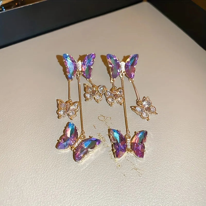 Silver electroplated alloy drop earrings with a blue purple butterfly charm and crystal flower details on a tassel.