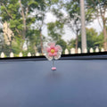 Small colourful plastic swing car decoration hanging ornament in blue, green, pink, purple, or yellow.