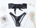 Black one-piece swimsuit with bikini print, split tube top, and backless design for women.