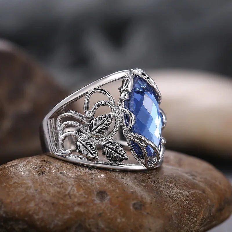 Blue crystal inlay on a geometric horse eye-shaped alloy ring for women.