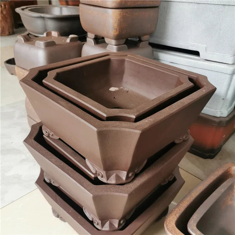 Two brown square stump purple sand flowerpots on a desktop with green plants