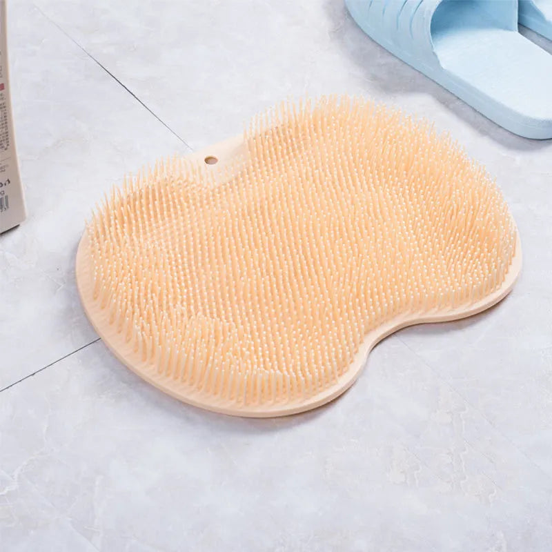 Orange silicone bath massage brush mat with suction cups on a bathroom floor