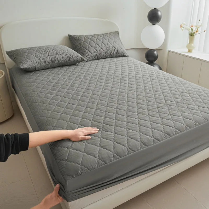 Diamond lattice quilted waterproof mattress protector fitted sheet in a solid colour on a bed.