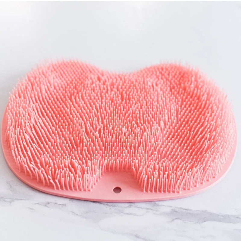 Orange silicone bath massage brush mat with suction cups on a bathroom floor