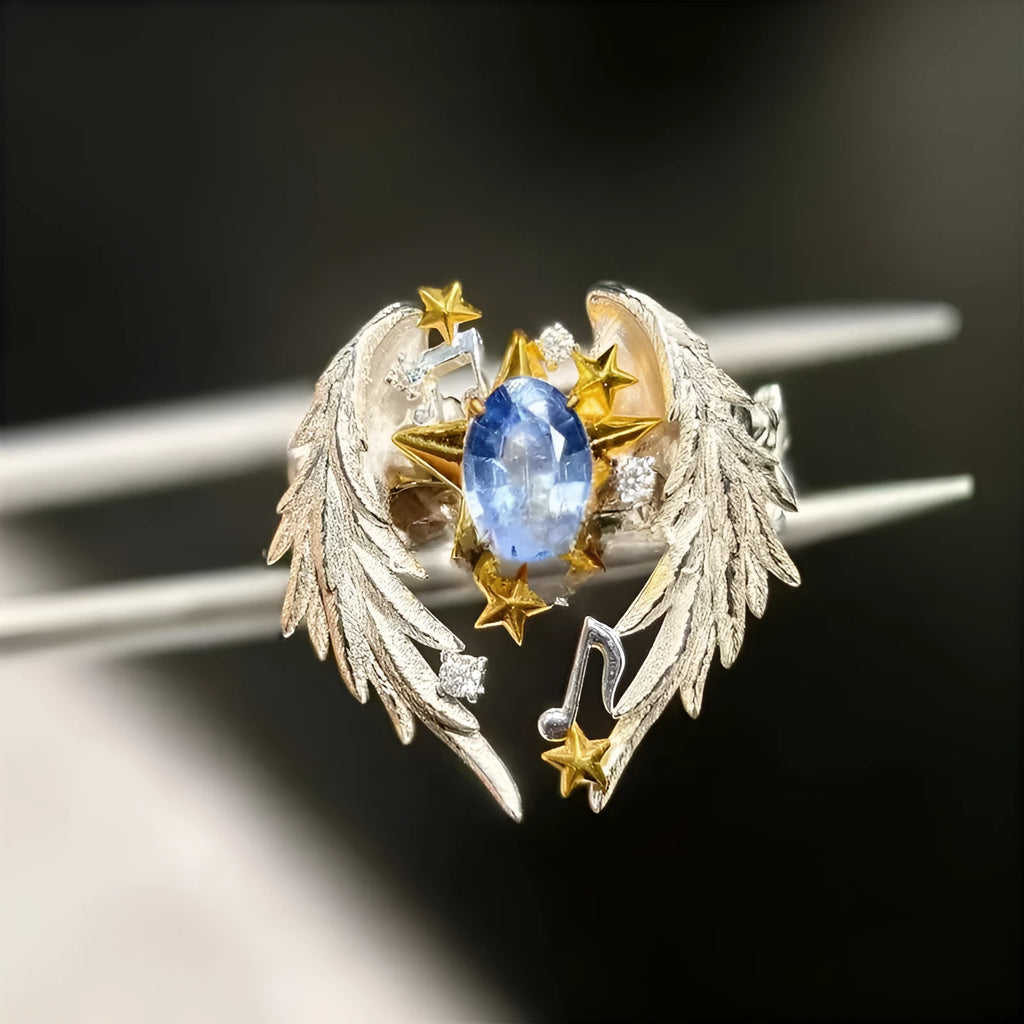 Gold-tone geometric angel wings alloy ring with adjustable opening on a finger.