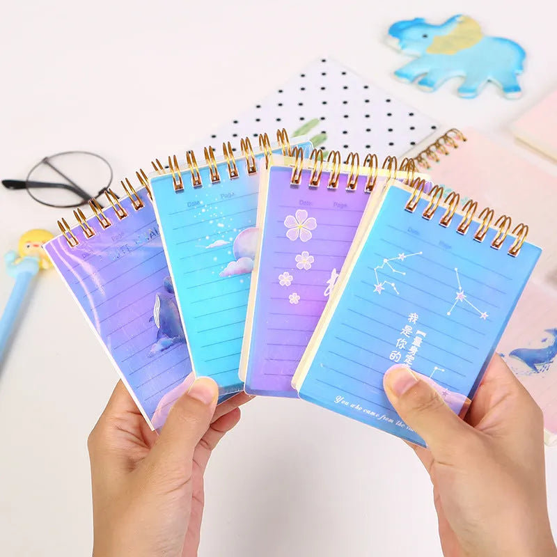 Set of four A7 spiral notebooks with different coloured PP plastic covers, showing spiral binding and open page.